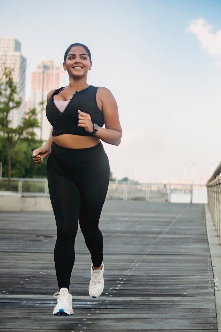 Smiling woman jogging on a city boardwalk, embodying a healthy lifestyle.